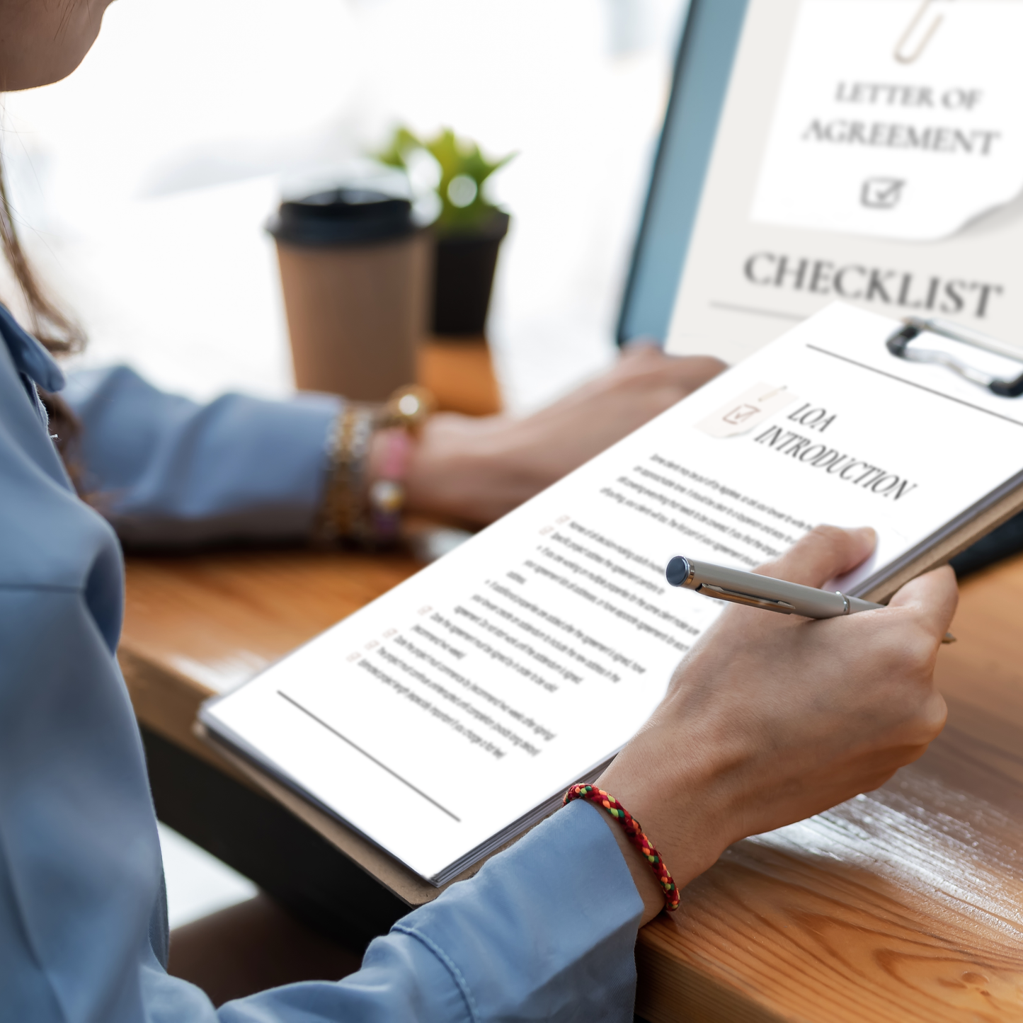 A person sitting at a table with a cup of coffee reviewing an interior design Letter of Agreement Checklist.