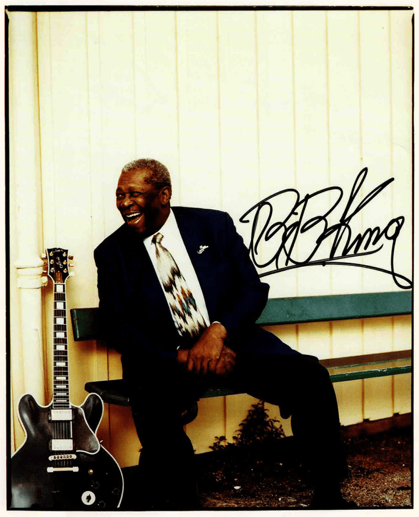 An autographed poster of B.B. King sitting on a bench with his guitar.